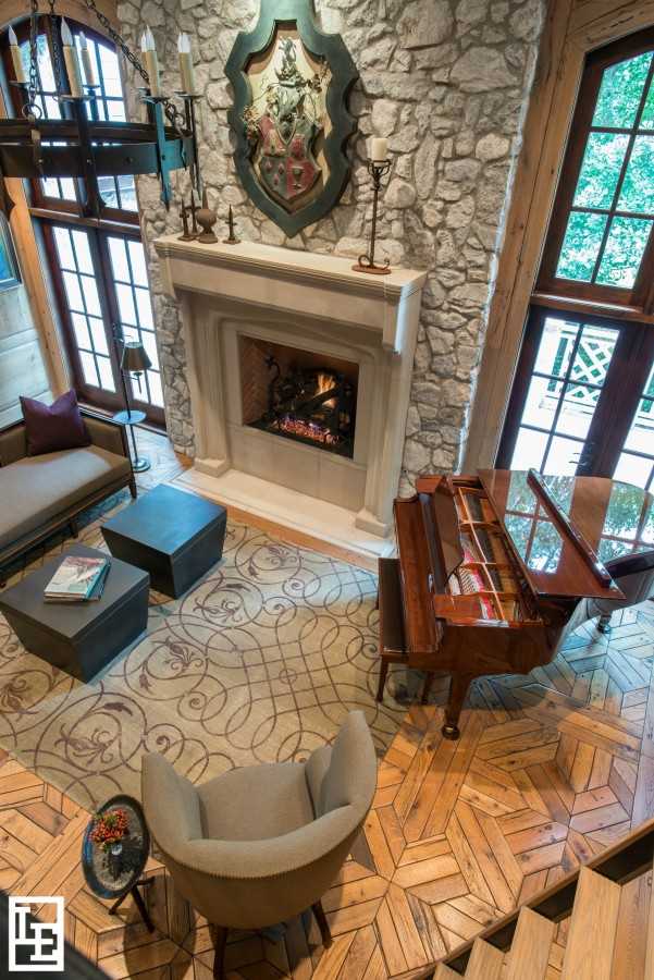 Texture and pattern are your friend. Here, the patterned wood floor, patterned rug, and textured wall behind the fireplace make this grand room feel warm and cozy.